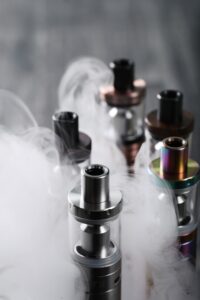 Tips of vape tanks with smoke swirling around them.